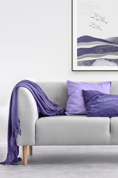 Pillows and purple blanket on grey sofa in white living room interior with gold table. Real photo; Shutterstock ID 1324000514; purchase_order: -; job: -; client: -; other: -