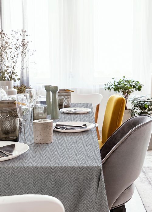 Real photo of table with dinnerware, candle and grey and yellow chair standing in bright dining room interior with window with curtains; Shutterstock ID 1228620817; purchase_order: -; job: -; client: -; other: -